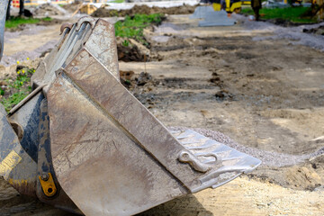 excavator bucket on the ground for digging for the construction of roads and parks in the city