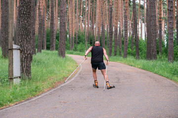Fototapeta premium an adult man rides on roller skis and pushes off the asphalt with sticks