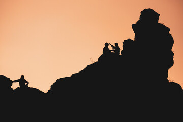 lovers are sitting on a rock and feeding each other from their hands. A stranger is standing nearby and waiting