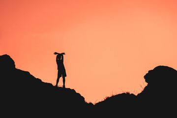 A man is standing on a hill with his arms outstretched