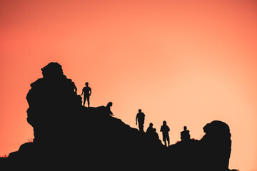 silhouettes of a group of people climbing a mountain