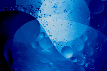 Macro photography of floating oil bubbles in blue fluid forming abstract wave patterns