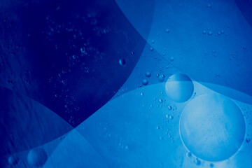 Close-up macro of blue oil and water bubbles forming abstract shapes