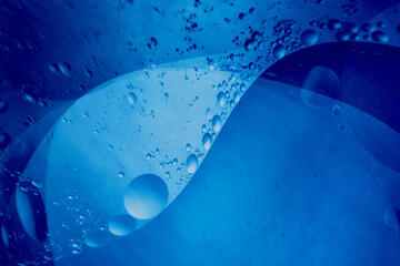 Abstract background of oil bubbles in blue liquid creating smooth shapes.