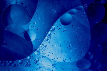 Close-up macro of blue oil and water bubbles forming abstract shapes