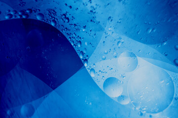 Abstract background of oil bubbles in blue liquid creating smooth shapes.