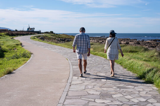 A couple walks along the coastal path from A Guarda toward the mouth of the Miño River. Pontevedra, Galicia - Powered by Adobe