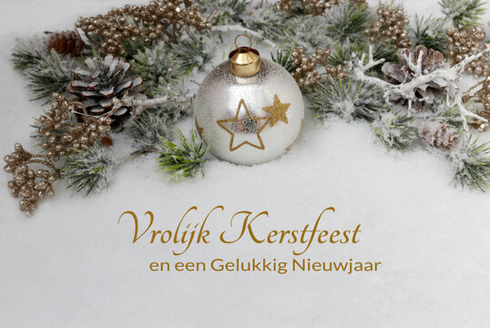 Kerstkaart: Kerstgroet in het Nederlands met kerstballen en dennentakken in de sneeuw. Prettige kerstdagen en een gelukkig nieuwjaar.