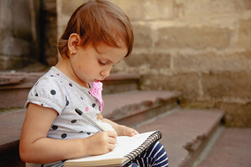 Little girl sketching under natural daylight.