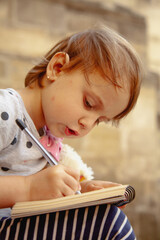 Girl expressing thoughts in a sketchbook outdoors.