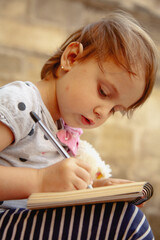 Soft daylight on a child drawing with a toy nearby. Vertical image.
