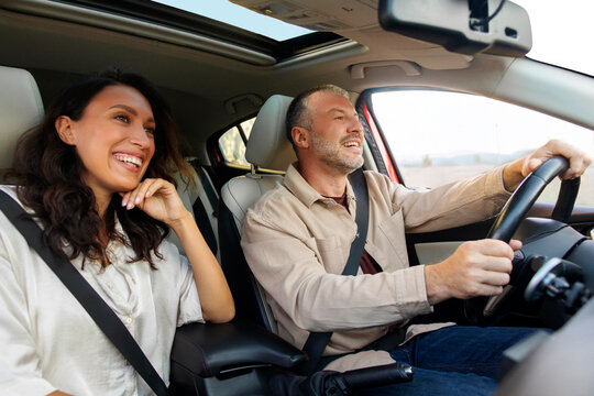 Excited European spouses going on vacation by automobile, sitting in nice brand new car, looking at road and smiling - Powered by Adobe