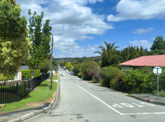 Quiet residential street in Riversdale South Africa with lush greenery and scattered clouds under blue sky