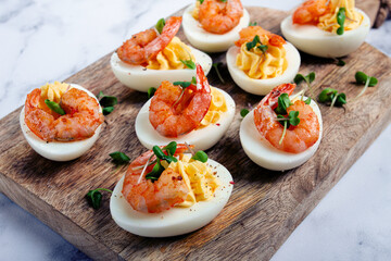 Boiled eggs stuffed with yolk and seasoned with mayonnaise, stuffed eggs with shrimp, on a wooden chopping board, selective focus, close-up, no people,