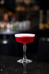 Classic clover club raspberry gin alcoholic cocktail in dark bar atmosphere with bokeh lights
