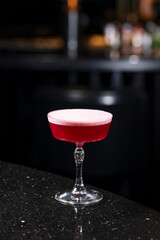 Classic clover club raspberry gin alcoholic cocktail in dark bar atmosphere with bokeh lights
