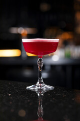 Classic clover club raspberry gin alcoholic cocktail in dark bar atmosphere with bokeh lights
