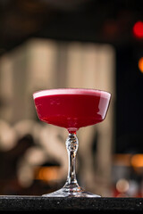 Classic clover club raspberry gin alcoholic cocktail in dark bar atmosphere with bokeh lights

