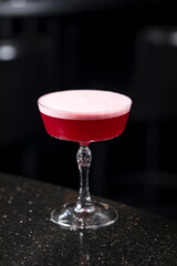 Classic clover club raspberry gin alcoholic cocktail in dark bar atmosphere with bokeh lights
