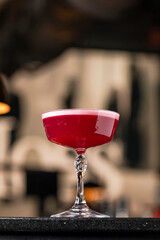 Classic clover club raspberry gin alcoholic cocktail in dark bar atmosphere with bokeh lights
