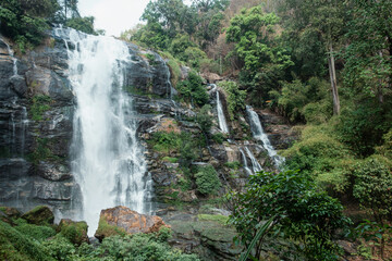 Powerful waterfall cascading down rugged cliffs deep within the lush rainforest of Doi Inthanon National Park, Chiang Mai, Thailand. Ecotourism, wilderness exploration and environmental conservation