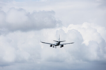 Commercial airplane approaching airport runway flying through thick white clouds under overcast sky on a daytime flight