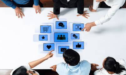Group of Business Professionals Collaborating Around Digital Touchscreen Displaying Various Icons Representing Communication, Marketing, and Social Media Strategies Trope.