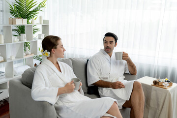 Obraz premium Beauty or body treatment spa salon vacation lifestyle concept with couple wearing bathrobe relaxing with drinks in luxurious hotel spa or resort room. Vacation and leisure relaxation. Quiescent