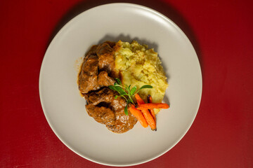 Stewed Iberian pork cheeks with creamy mashed potatoes, a tender and flavorful traditional dish from Spanish and Portuguese cuisine.