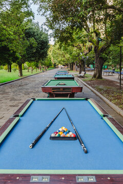View of billiards tables line a serene, tree-lined park path, cues poised above the colorful balls, inviting a game amidst lush greenery, Batumi, Adjara, Georgia.