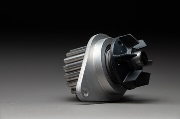 Top-quality parts for your car. Car maintenance. New water pump for a car's engine cooling system on a gray gradient background.