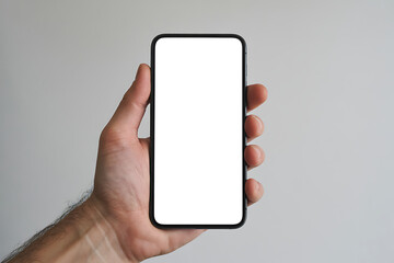 Close up of a person s hand holding a modern smartphone with a blank white screen against a neutral background