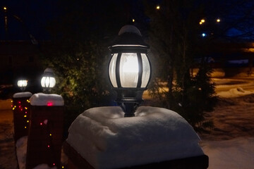 street lamps covered in snow, burning in the darkness