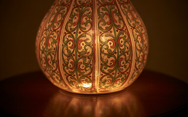 Ornate glass lamp with intricate patterns glowing softly on a wooden table creating a warm ambiance