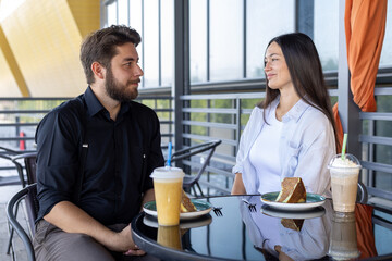 Man and woman sitting at a table, smiling and enjoying a meal together 