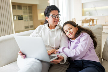 Fototapeta premium Mother and daughter enjoy time together while using a laptop at home