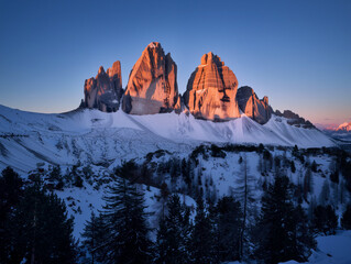 Snowy mountains at dawn with alpenglow on jagged peaks under a clear blue winter sky. Generative AI