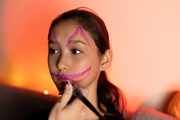Girl with purple and yellow face paint smiling brightly