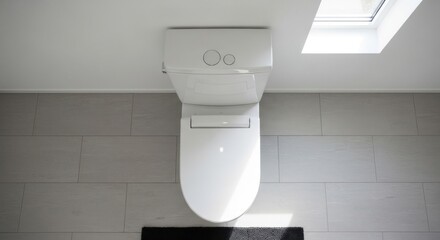 A modern white toilet is centered in a bathroom with light gray tiles and a skylight above.
