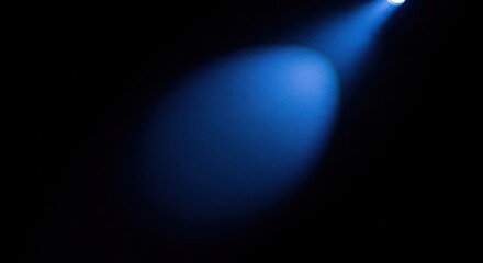 A bright blue spotlight illuminates a dark background, creating a dramatic effect.