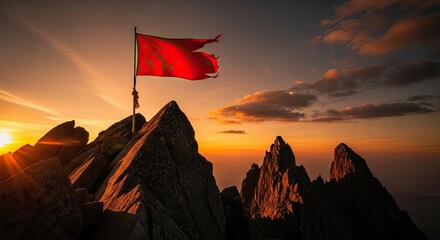 Red flag waving on a rocky mountain summit at sunset golden hour