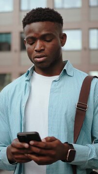Young man looks at mobile phone with sad expression
