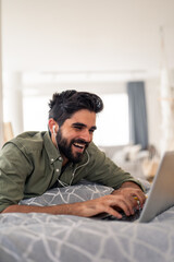 Relaxed young man working and talking on phone indoors with bright natural light and laptop