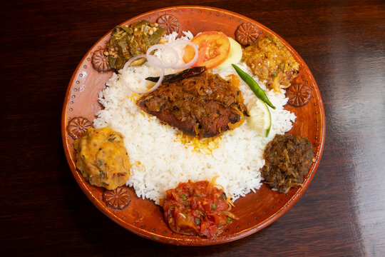 Ilish Thali or Bengali Hilsa Fish Meal with Bhortas, Rice, and Assorted Side Dishes on Rustic Plate side view of bangladeshi food