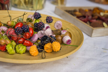 a wooden bowl filled with colorful decorative craft berries, pods, and simulated acorns used for autumn floral arrangements, floral arrangement supplies, diy craft material, seasonal home decor