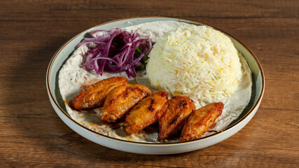 Chicken wings kebab with rice and red onions on lavash