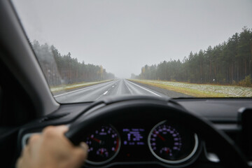 View of a foggy road from a car window and dashboard