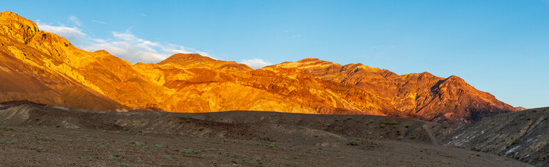 Panoramic View of Golden Sunset on Mountains with Rocky Wash and Desert Plants, Death Valley National Park