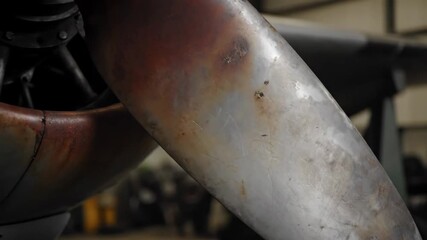 Close-Up of an Aircraft Propeller Blade - This video captures a close-up view of an aircraft propeller blade, showcasing its weathered metallic surface with noticeable scratches and rust. - Powered by Adobe