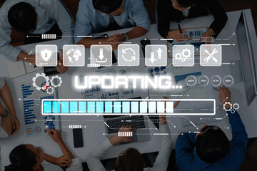 A diverse team collaborates in a modern workspace, engaged in updating data and analyzing performance through digital interfaces and visual presentations. Trope